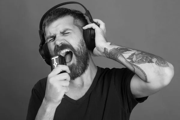 Man sings on green background. Singer with beard and excited face listens to music.