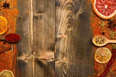 Çeşniler kavramı. Tarçın, kırmızı biber ve curcuma dolu kaşık ahşap arka planda, kopya alanı yatıyordu. Çeşniler tüm yüzey üzerinde dağınık. Baharatlar ve kuru malzemeler ahşap doku