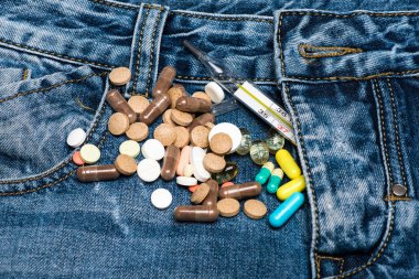 İlaç veya ilaç tablet kot yakınındaki ZIP, denim arka plan üzerinde dağınık. Genitoüriner sorun kavramı. Renkli hapları ve cıva termometre ile Genitoüriner sistem bozuklukları sembolü olarak zip