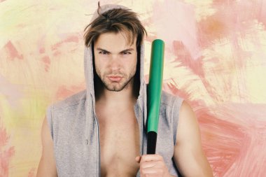 Parlak yeşil yarasa adam gri kolsuz hoodie içinde tutar. Sokak hayat, tehlike ve suç kavramı. Yarı çıplak vücut renkli arka plan üzerinde olan adam.