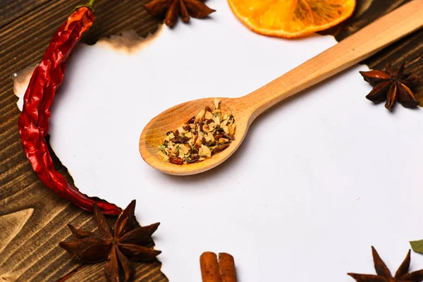 Trozo de papel sobre fondo de madera. Especias, hierbas de cocina yacen alrededor del papel blanco. Canela, naranja seca y pimienta, anís estrellado yacen alrededor de papel en blanco para la receta, espacio de copia. Concepto de receta culinaria — Foto de Stock