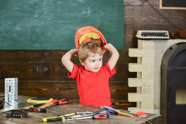 그의 머리 위에 오렌지 보호 헬멧을 들고 작은 소년. 꼬마 작업 장비와 함께 연주입니다. 미 취학 아동 워크숍에서 재미 — 스톡 사진