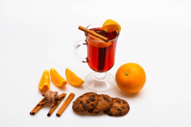 Sonbahar içecek konsepti. Cam mulled şarap veya içki yakınındaki beyaz arka plan üzerinde sulu turuncu meyve ile kapatın. İçki ya da içecek tarçın, portakal meyve ve çikolata damla ile tanımlama