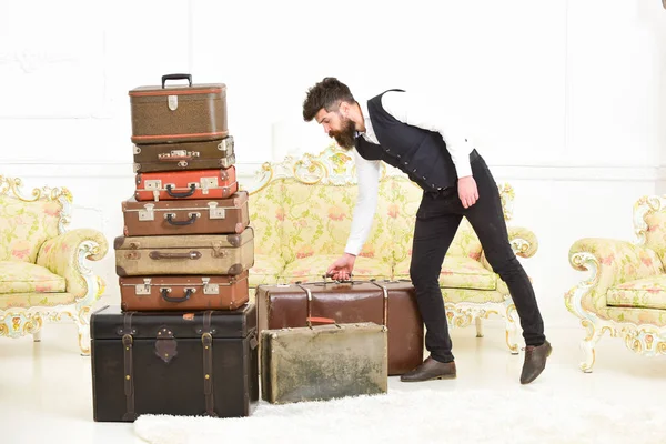 Macho elegant im strengen Gesicht trägt Vintage-Koffer. Mann, Butler mit Bart und Schnurrbart im klassischen Anzug liefert Gepäck, luxuriöser weißer Innenraum. Gepäck- und Umzugskonzept — Stockfoto