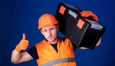 Onarım istişare kavramı. Kask, kask içinde adam araç kutusu tutar ve yukarı hareketi, mavi arka plan gösterir. İşçi, repairer, tamirci, emin yüz taşıyan araç omuz üzerinde Oluşturucu