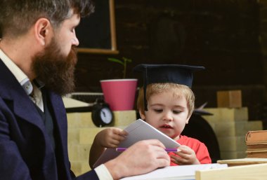 İlköğretim kavramı. Çocuk çalışmaları dikkatle dinlerken öğretmen ile. Öğretmen ve öğrenci kolej, kara tahta arka plan içinde. Baba oğul öğretir temel bilgi, tartışmak, açıklamak