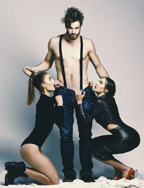 Ο τύπος με γυμνό κορμό μυϊκή και δύο φίλες sexi άνθρωπος και όμορφα κορίτσια με επιθυμώντας να αντιμετωπίζει σε γκρίζο φόντο — Φωτογραφία Αρχείου