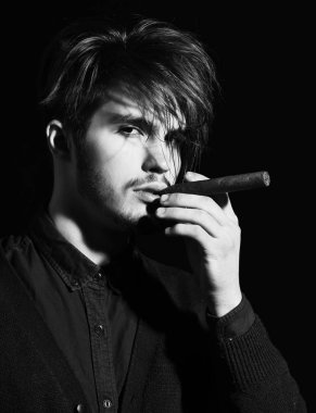 Ciddi sakallı adam puro içiyor.