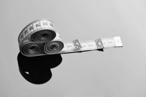 Measuring tape rolls placed on each other on mirror background — Stock Photo, Image