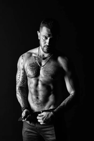 Sportsman with six pack and ab. Fashion model buckle leather belt in jeans. Man with tattoo design on skin. Bearded man shirtless with fit torso. Fitness with sport and bodycare, black and white — Stock Photo, Image