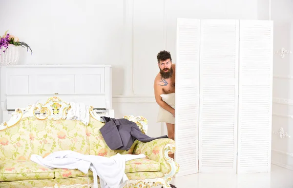 Hipster nackt auf schockiertem Gesicht unerwartet im Schlafzimmer entdeckt. Liebeserklärung. Mann mit Bart und Schnurrbart versteckt sich hinter Klappscheibe. Mann, Liebhaber in weißem Interieur nackt erwischt — Stockfoto