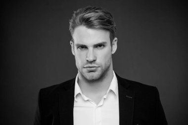 Olarak, onun görünümünü kendine güvenen bir adam. Güven ve erkeklik. Kıl ve saç modeli ile de bakımlı adam gri arka plan. Maço emin katı yüz kapatın. Adam yakışıklı çekici formal giyim