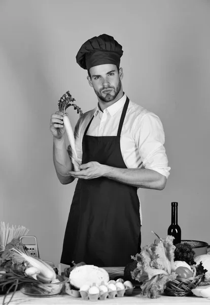 Mannen i kock hatt och förkläde med Rädisa. Köket och professionell matlagning koncept. Cook fungerar i köket — Stockfoto
