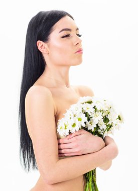 Bayan göğüsler üzerinde beyaz izole çiçekli kapsar. Sağlıklı ciltle pürüzsüz kadınla çekici görünüyor. Sakin yüz kız çıplak durumda ve papatya çiçeği göğüs önünde tutar. Cilt sağlığı kavramı