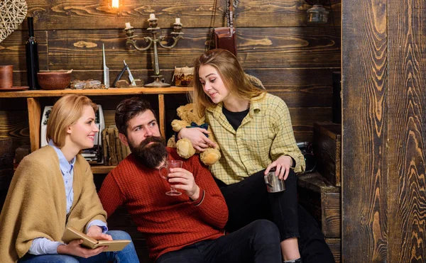 Leseratten lesen zusammen auf der Couch. Eltern und halbwüchsige Tochter verbringen Weihnachten auf dem Land. Ein bärtiger Mann trinkt an einem Winterabend Glühwein. Neugieriges Mädchen schaut ihren Vater an — Stockfoto