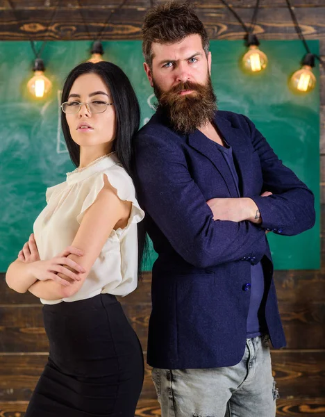 Adam sakallı ve öğretmen stand sırt sırta, kara tahta arka plan ile. Okul personeli kavramı. Öğretmen, öğretmen bak kendine güvenen. Akıllı bir adam ve yeşil arka plana karşı duran kadın portre