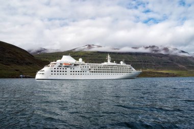 Zevk için seyir. Cruise gemi denizde dağ manzarası Sejdisfjordur, İzlanda üzerinde. Okyanus gemisi denizde dağlar bulutlu gökyüzü üzerinde. Yaz tatil ve gezi. Macera ve keşif