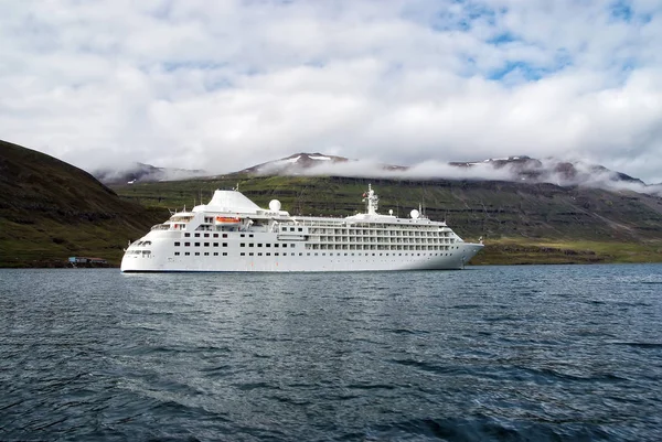 Zevk için seyir. Cruise gemi denizde dağ manzarası Sejdisfjordur, İzlanda üzerinde. Okyanus gemisi denizde dağlar bulutlu gökyüzü üzerinde. Yaz tatil ve gezi. Macera ve keşif