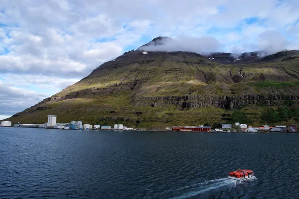 İzlanda gezisi. Sejdisfjordur, İzlanda dağ manzarası denizde tekne float. Bulutlu gökyüzü dağda ile yalı. Su ile seyahat. Macera ve keşif. Yaz tatil ve yolculuk tutkusu