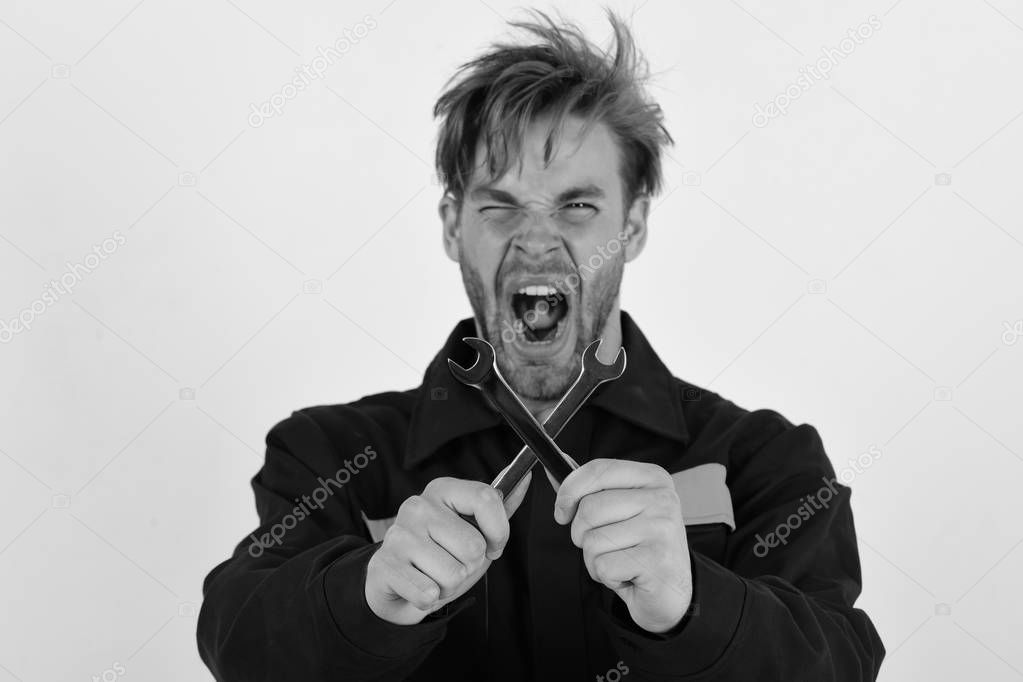 Man with mad face holds wrench tools crossed on white background. Maintenance and repairing concept. Mechanic or plumber with metallic spanner