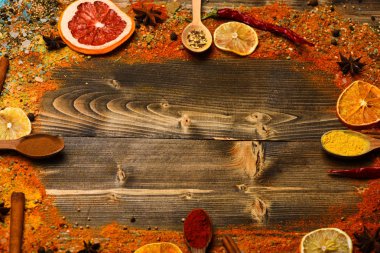 Çeşniler kavramı. Tarçın, kırmızı biber ve curcuma dolu kaşık ahşap arka planda, kopya alanı yatıyordu. Baharatlar ve kuru malzemeler ahşap doku. Tüm yüzey üzerinde dağınık çeşniler