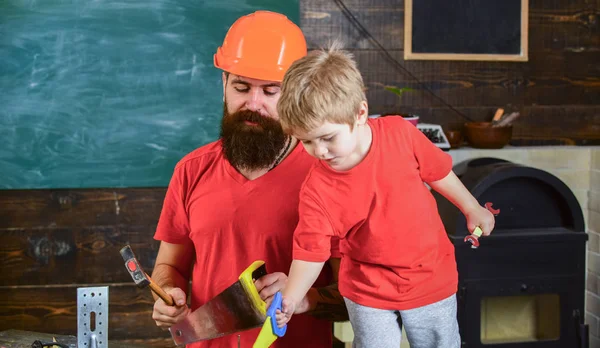 Evlat, çocuk oyuncakla oynamak neşeli, öğrenme kullanım araçları babamla gördüm. Baba, üst koruyucu kask okul atölyesinde farklı araçları kullanmak için küçük oğlu öğretim içinde sakallı. Babalık kavramı