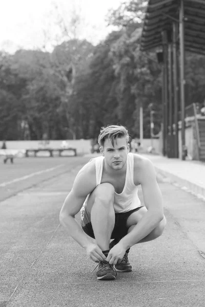 Concept de marathon et de compétition. Sportsman attache ses entraîneurs assis et se prépare à courir — Photo