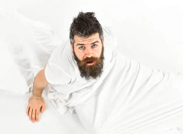 Hombre con la cara soñolienta sentarse en la cama, sábanas blancas —  Fotos de Stock