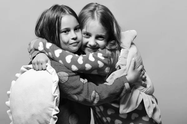 Pajama party and childhood concept. Girls with loose hair hug. Kids with smiling faces