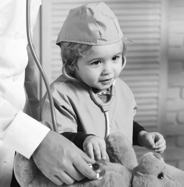 Pequeño asistente examinar osito de peluche. Padre e hijo con cara curiosa y feliz jugando al doctor . — Foto de Stock