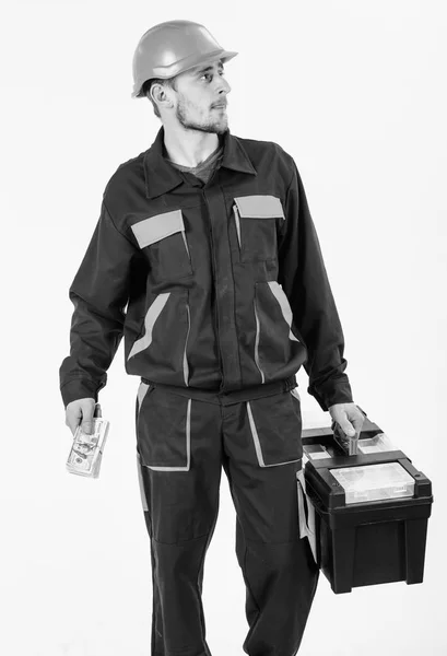 Homem com caixa de ferramentas anda, tem dinheiro. Construtor detém dinheiro, reparador detém dinheiro, notas na mão . — Fotografia de Stock