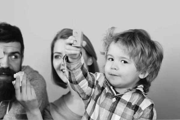 Enfance et concept de jeu. Homme avec barbe, femme et garçon jouent sur fond bleu.. Famille avec des visages curieux passer du temps dans la salle de jeux — Photo