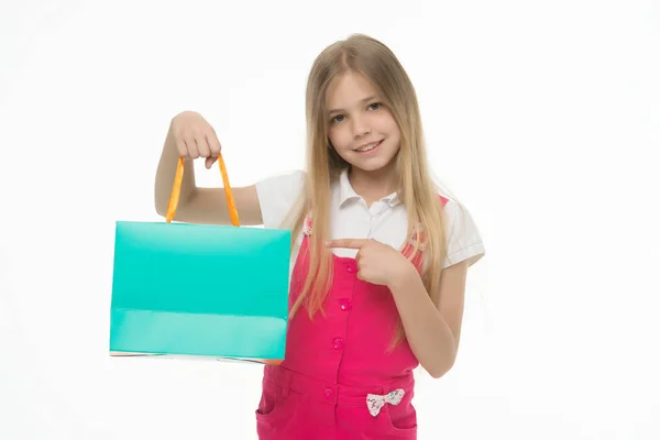 Szczęśliwe dziecko punkt palcem ar torba na zakupy na białym tle. Mała dziewczynka zakupoholiczki prezentacji produktu z worka papierowego. Shopper mody. Przygotowania do Świąt i uroczystości. Zakupy, sprzedaż, kopiować miejsca — Zdjęcie stockowe