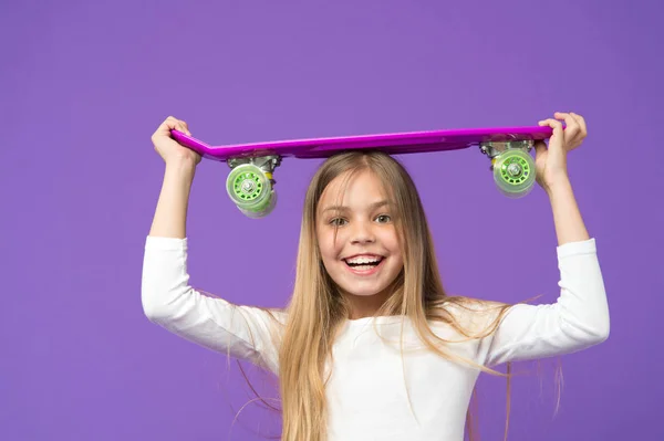乗る準備ができています。スケート ボードは楽しいです。紫色の背景の女の子が幸せなスケーター。児童の発達と幸福。内気な少女。小さな子供は、ペニー ボードと笑顔します。アクティブな趣味とスポーツ活動 — ストック写真