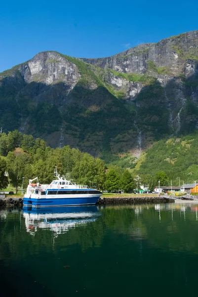 Barco de placer en el muelle del mar en el paisaje de montaña en Flam, Noruega. Pequeño barco en puerto marítimo con montañas verdes. Viajando por agua. Vacaciones de verano y vacaciones. Vagabundo y descubrimiento — Foto de Stock