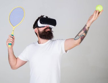 Vr gözlük, gri arka planda sakallı adam. Hipster konsantre yüzündeki spor oyunları için modern teknolojisini kullanıyor. Sanal Tenis kavramı. Vr gözlüklü play tenis raket ve top ile