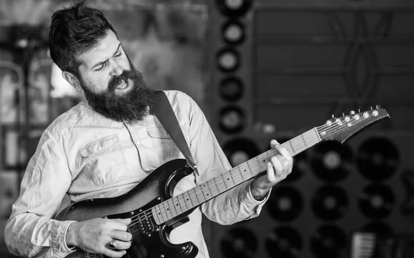 Musician with beard play electric guitar. Rock music concept. Talented musician, soloist, singer play guitar in music club on background. Man with shouting face play guitar, singing song, play music.