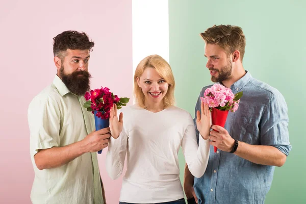 Men competitors with bouquets flowers try conquer girl. Girl smiling reject gifts. Feminism concept. Woman smiling reject both male partners. Out of relations. Girl popular receive lot men attention