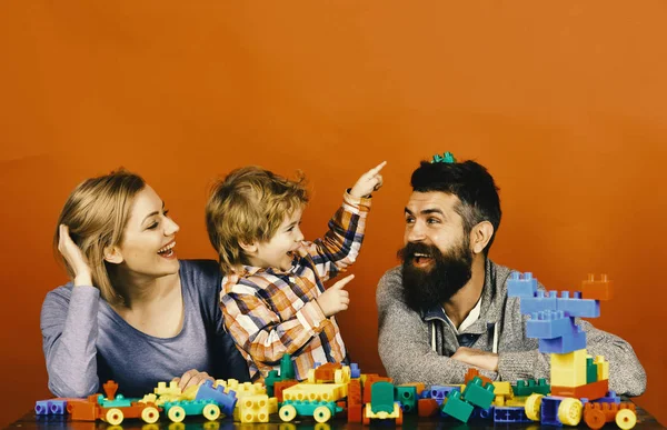 Οικογένεια με χαρούμενα πρόσωπα οικοδομήσουμε αυτοκίνητα παιχνιδιών από χρωματιστό κατασκευή μπλοκ. Μητρότητα και παιχνίδι έννοια. Άντρας με γένια, γυναίκα και αγόρι — Φωτογραφία Αρχείου