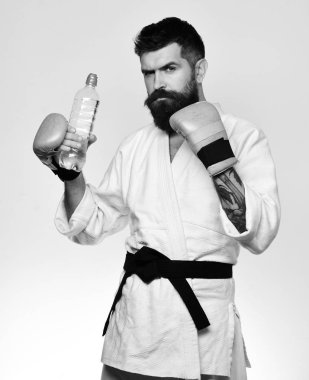 Boks eldivenleri ciddi yüzüne adamla karate su şişesi tutar. Oryantal spor kavram. Savaş ana içecekler su yenileniyor