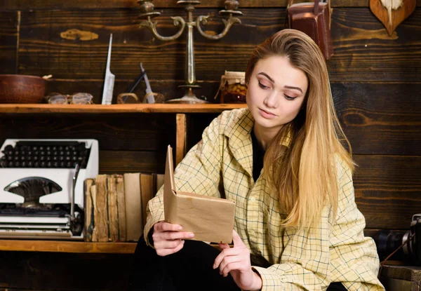 Студентка учится с книгой в доме егеря. Девушка в повседневной одежде сидит с книгой в деревянном винтажном интерьере. Концепция обучения. Леди на спокойном лице в клетчатой одежде выглядит мило и непринужденно — стоковое фото