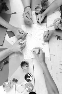 Sanatçı ahşap masa boyalar ve renkli kağıt ile. Yaratıcılık ve sanat kavramı. Eller renkli işaretleri tutun ve çizin