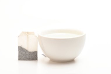 Kupa su ve çay poşeti beyaz zemin üzerine kaynar ile dolu. Fincan ya da beyaz Porselen Kupa şeffaf sıcak su ve çay kuru çanta ile. Çay zaman kavramı. Süreç içinde seramik kupa demleme çay