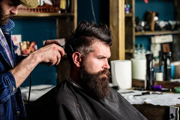 Barbiere con tagliacapelli lavora sull'acconciatura per uomo con barba, sfondo barbiere. Capelli da barbiere del cliente barbuto con pettine e clipper. Concetto di taglio. cliente hipster ottenere taglio di capelli — Foto Stock