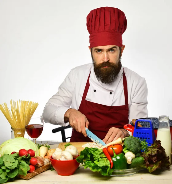 Kocken man skära grönsaker till sallad. Laga i röd uniform — Stockfoto