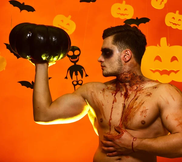 Adam göğüs üzerinde kan olan siyah kabak tutar.