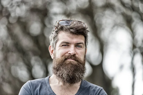 Hombre barbudo haciendo caras graciosas, frunciendo el ceño y levantando la ceja. Primer plano retrato de hombre guapo con barba larga al aire libre, divertido y activo concepto de ocio — Foto de Stock