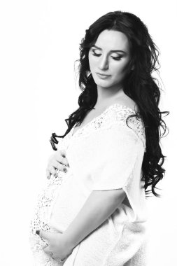 Güzel, hamile bir kadın karnını okşuyor.