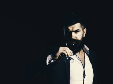 Takım elbise köpüklü kadeh kırmızı şarap ile toasting adam. Sommelier şarap rengi arka plan üzerinde sakallı. Yüz ve şarapdenemeye kavramı