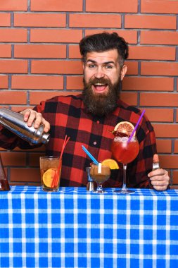 Adam shaker tuğla duvar arka plan üzerinde tutar. Barmen sakal ve mutlu yüz ile kokteyl yapar. Barmen veya hipster buz ve saman ile taze içecek yapar. Şık barmen kavramı